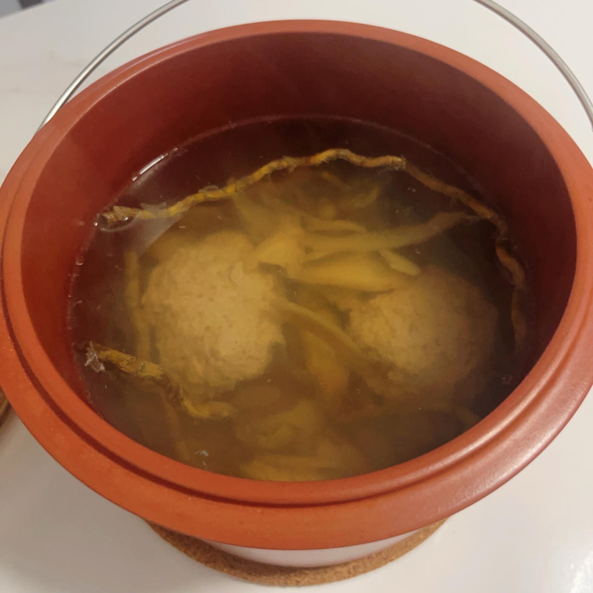Clear golden American ginseng dendrobium lean pork soup served in a small white bowl