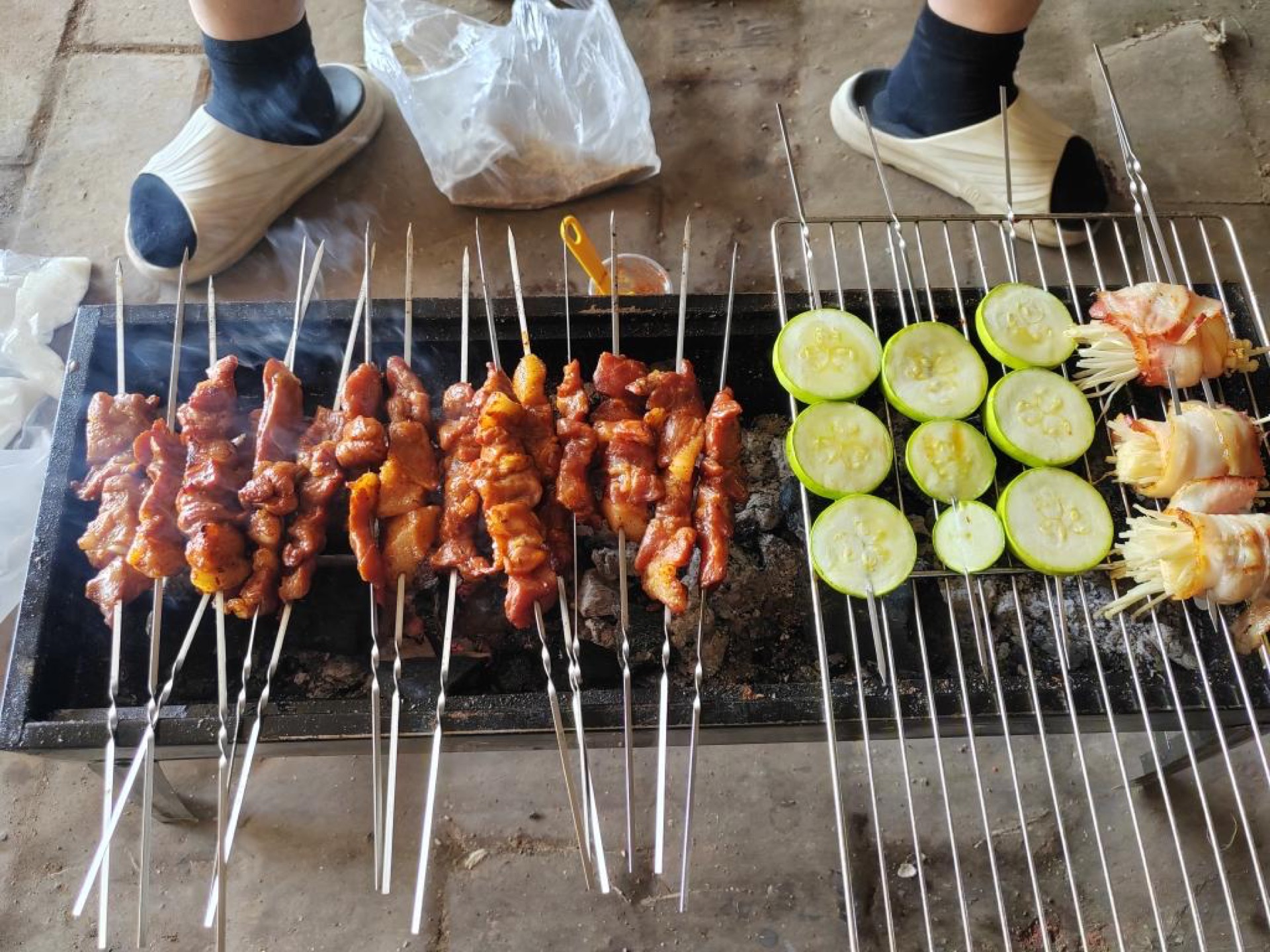 Pork skewers and bacon enoki cooking on the grill