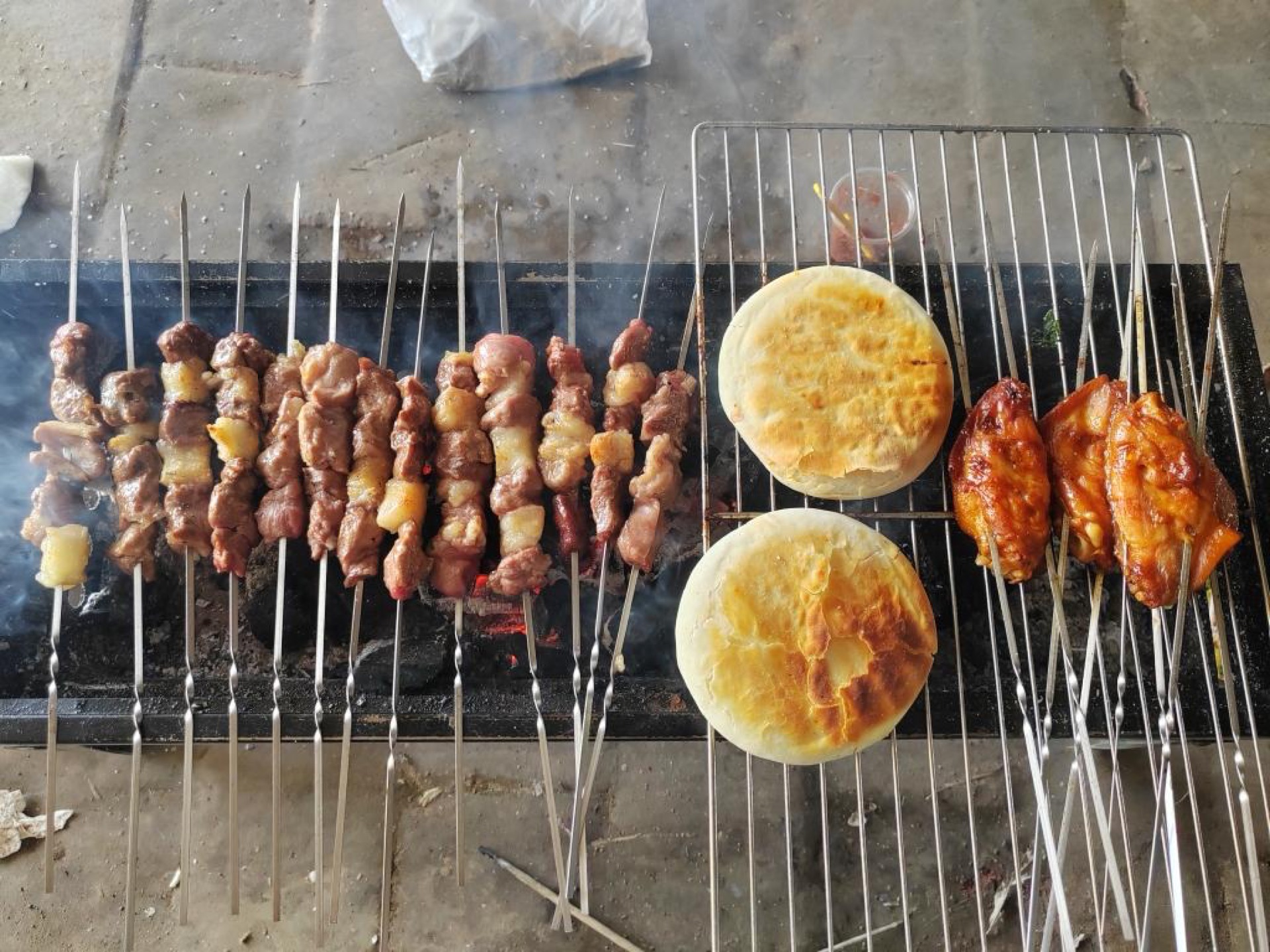 Lamb skewers and chicken wings on the grill
