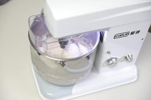 Sticky dough kneading in the mixer being checked for temperature