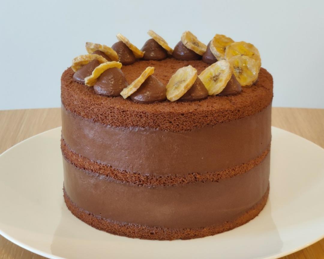 Finished cake topped with piped chocolate cream and roasted banana slices