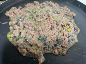 Cook the marinated ground beef in a hot wok until fully browned and cooked through.