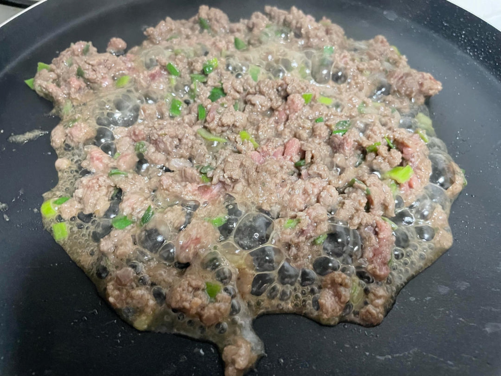 Cook the marinated ground beef in a hot wok until fully browned and cooked through.