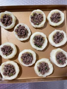 Once the potato cups come out of the oven, spoon the cooked ground beef into each cup.