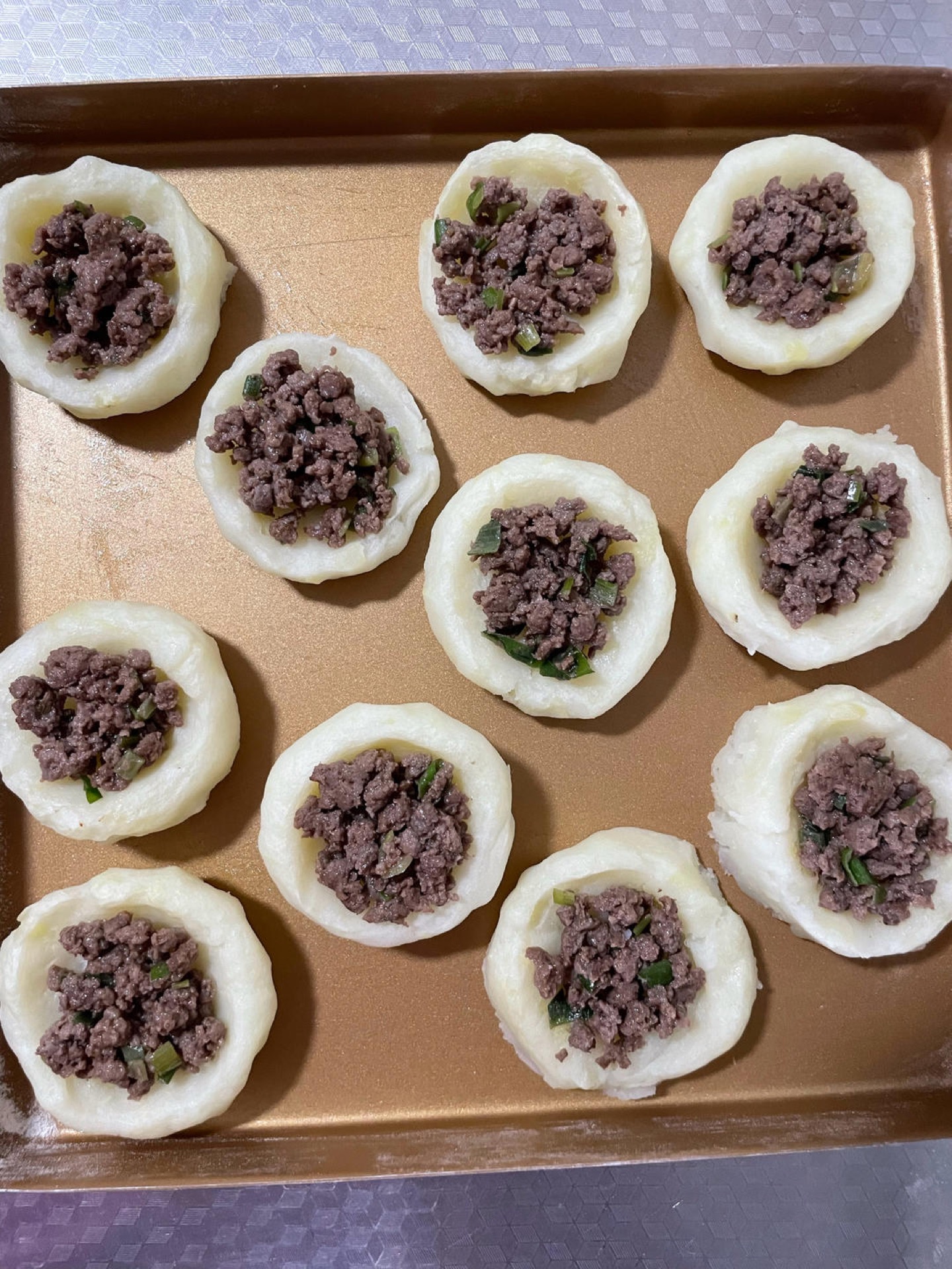 Once the potato cups come out of the oven, spoon the cooked ground beef into each cup.