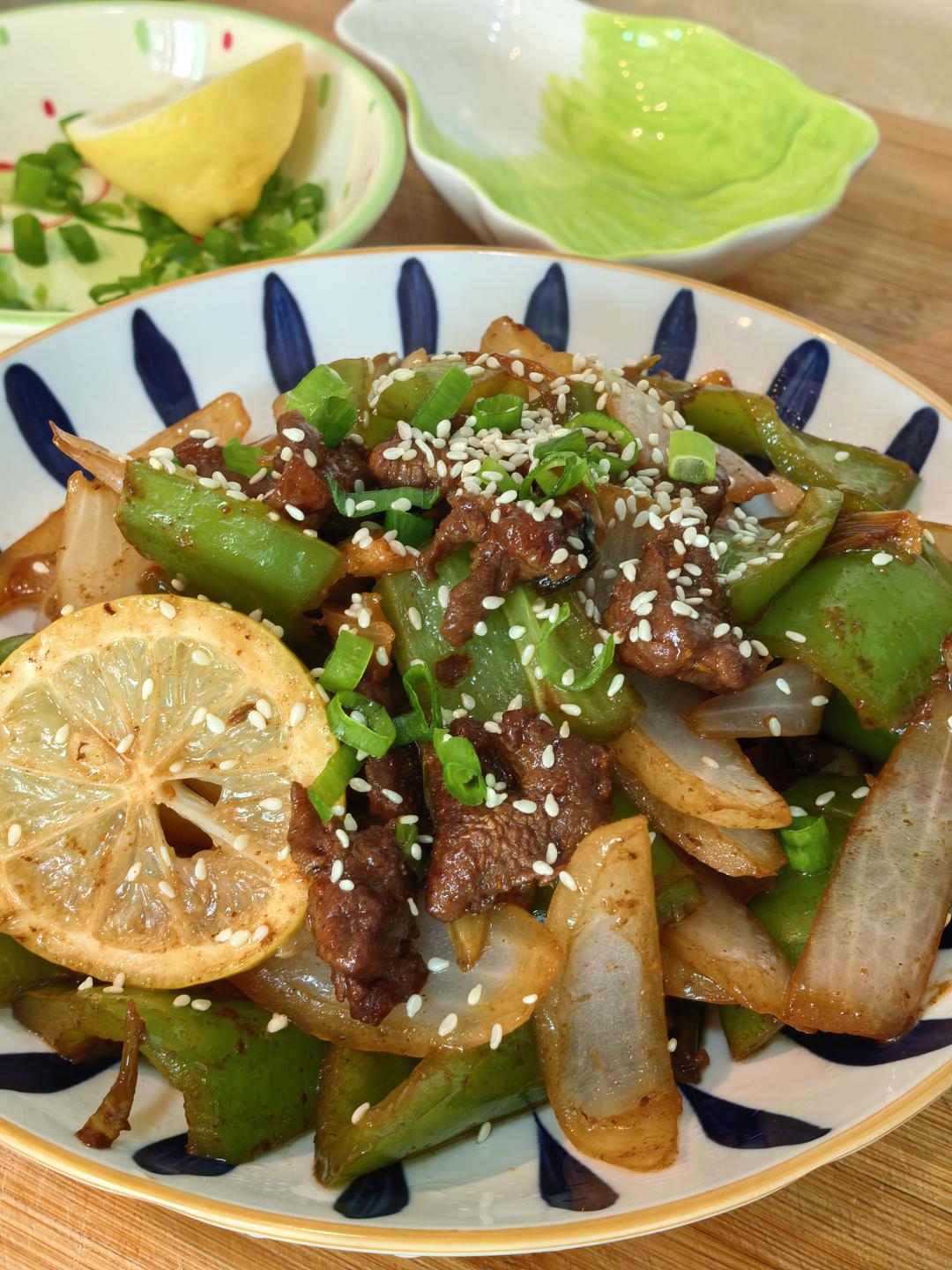 Plating the beef stir fry with scallion and sesame garnish