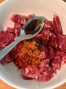 Pouring extra oil into the seasoned beef marinade