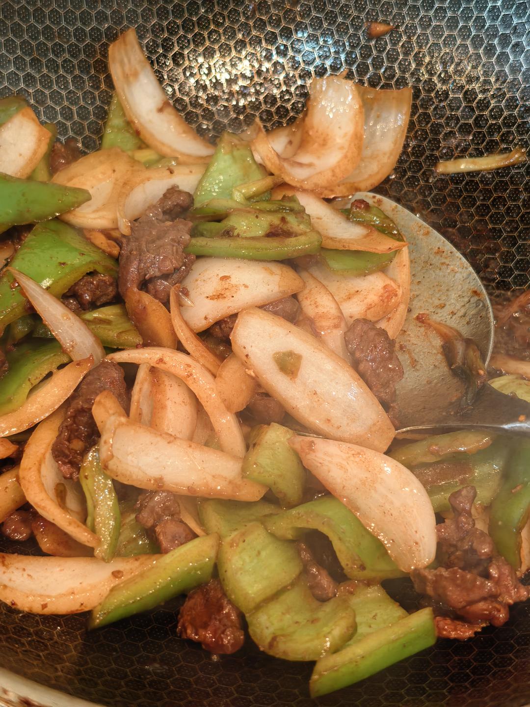 Adding green pepper and onion to the wok with the beef