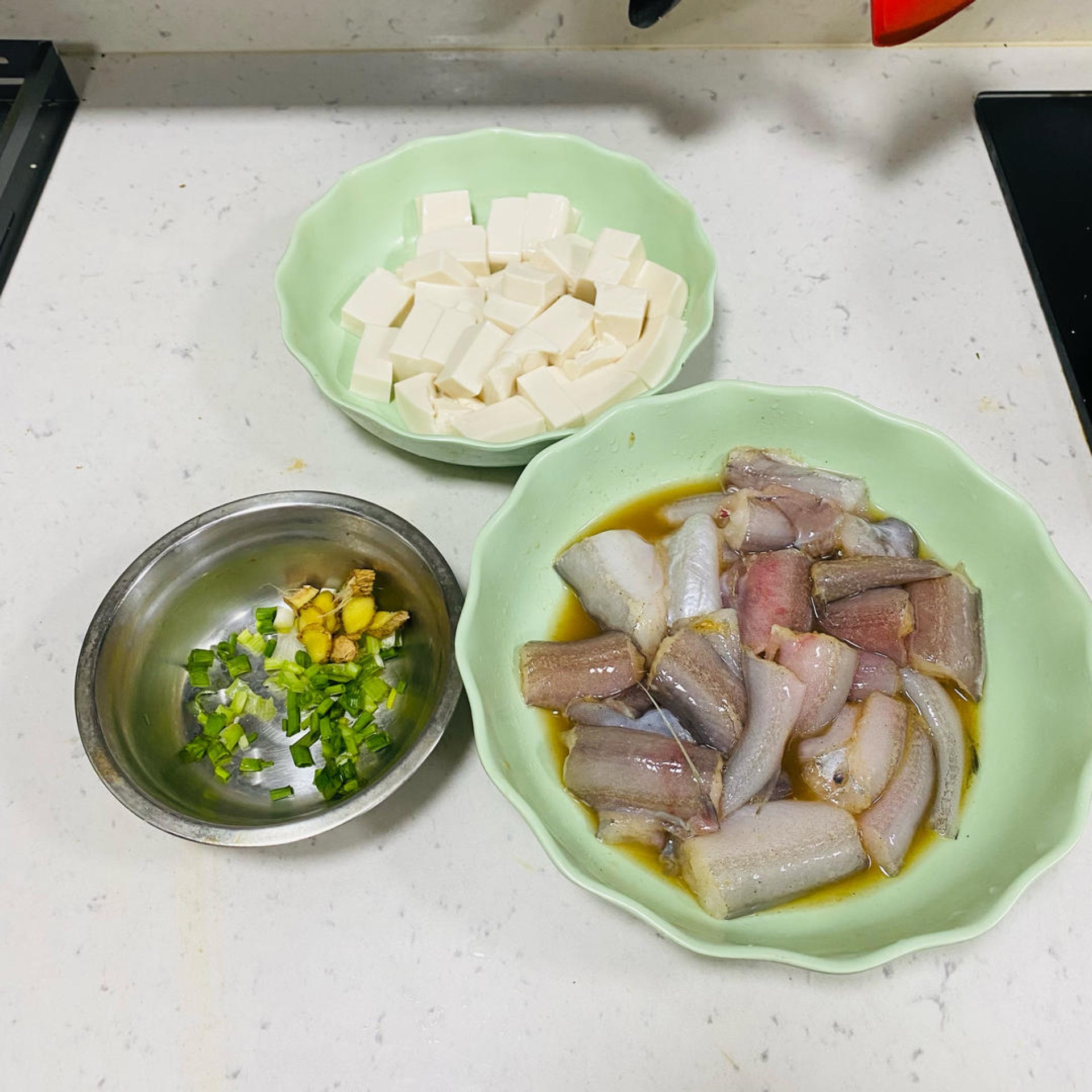 Prepare the ginger slices and chopped scallion, and cut the silken tofu into cubes.