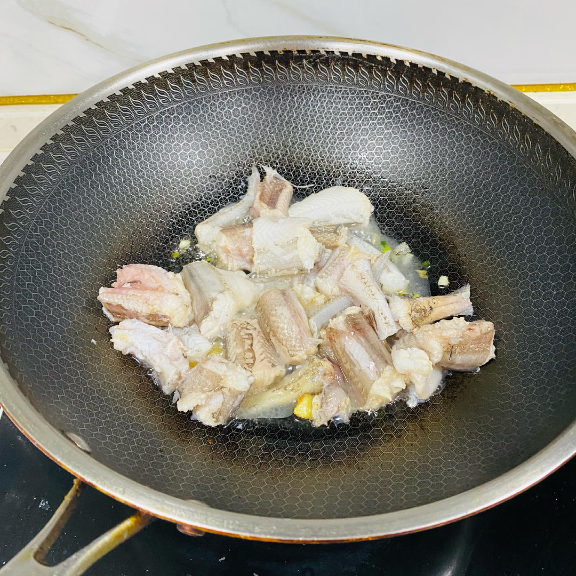 Gently push the wok to move the fish around and fry it for a moment.