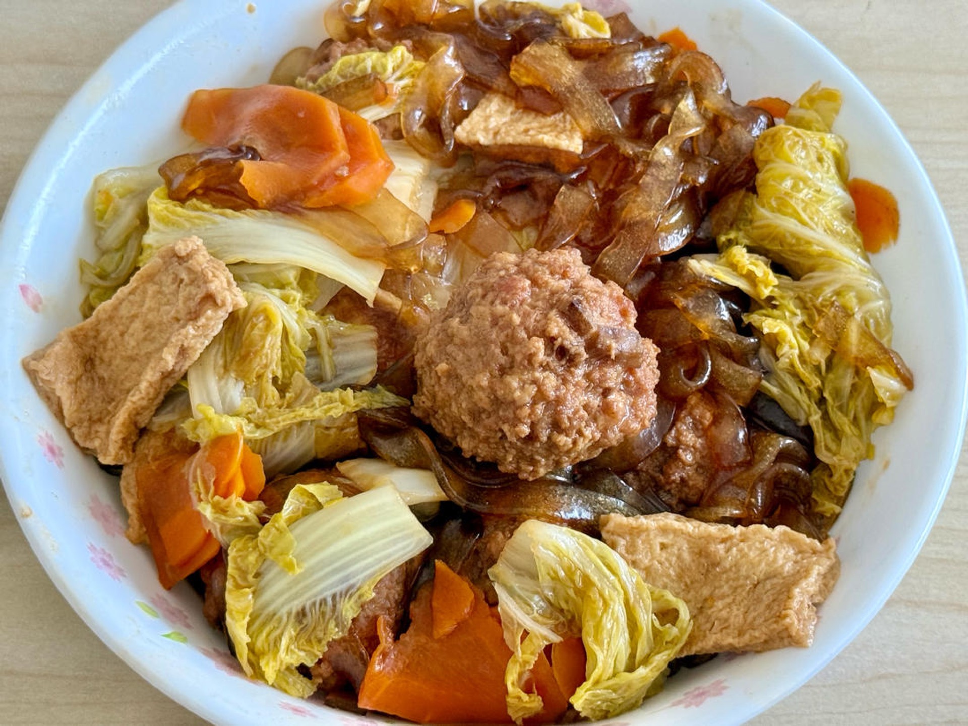 Braised cabbage vermicelli with meatballs in a shallow pot, garnished with scallions
