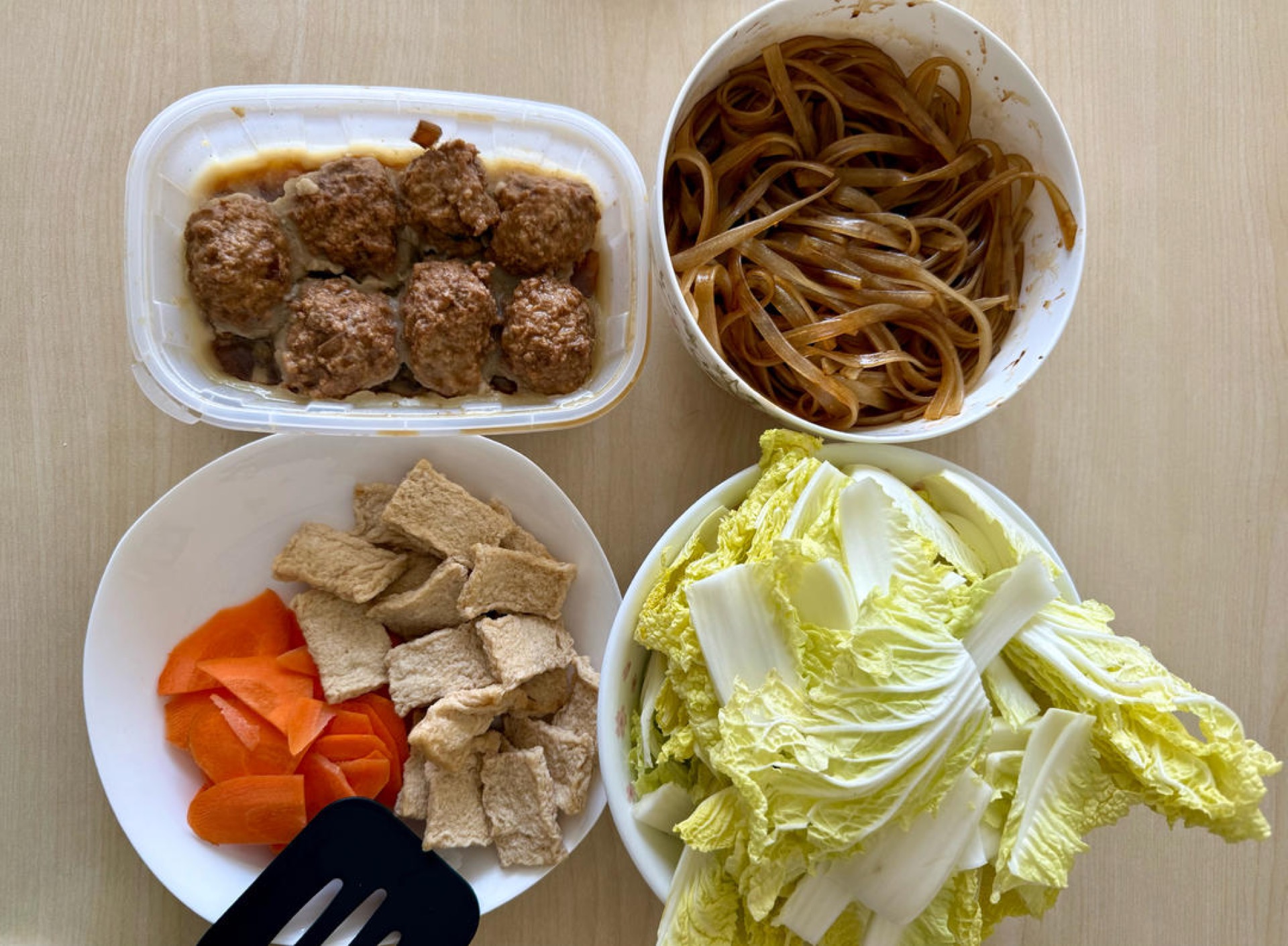 Soak the vermicelli in hot water until pliable, drain, and toss with dark soy sauce to color; cut the baby napa into chunks and slice the carrot.