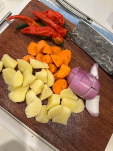 Cut the onion, potatoes, and carrot into rolling chunks, and the chili peppers into pieces. (King oyster mushrooms, shiitake mushrooms, lettuce stems, lotus root slices, and corn c