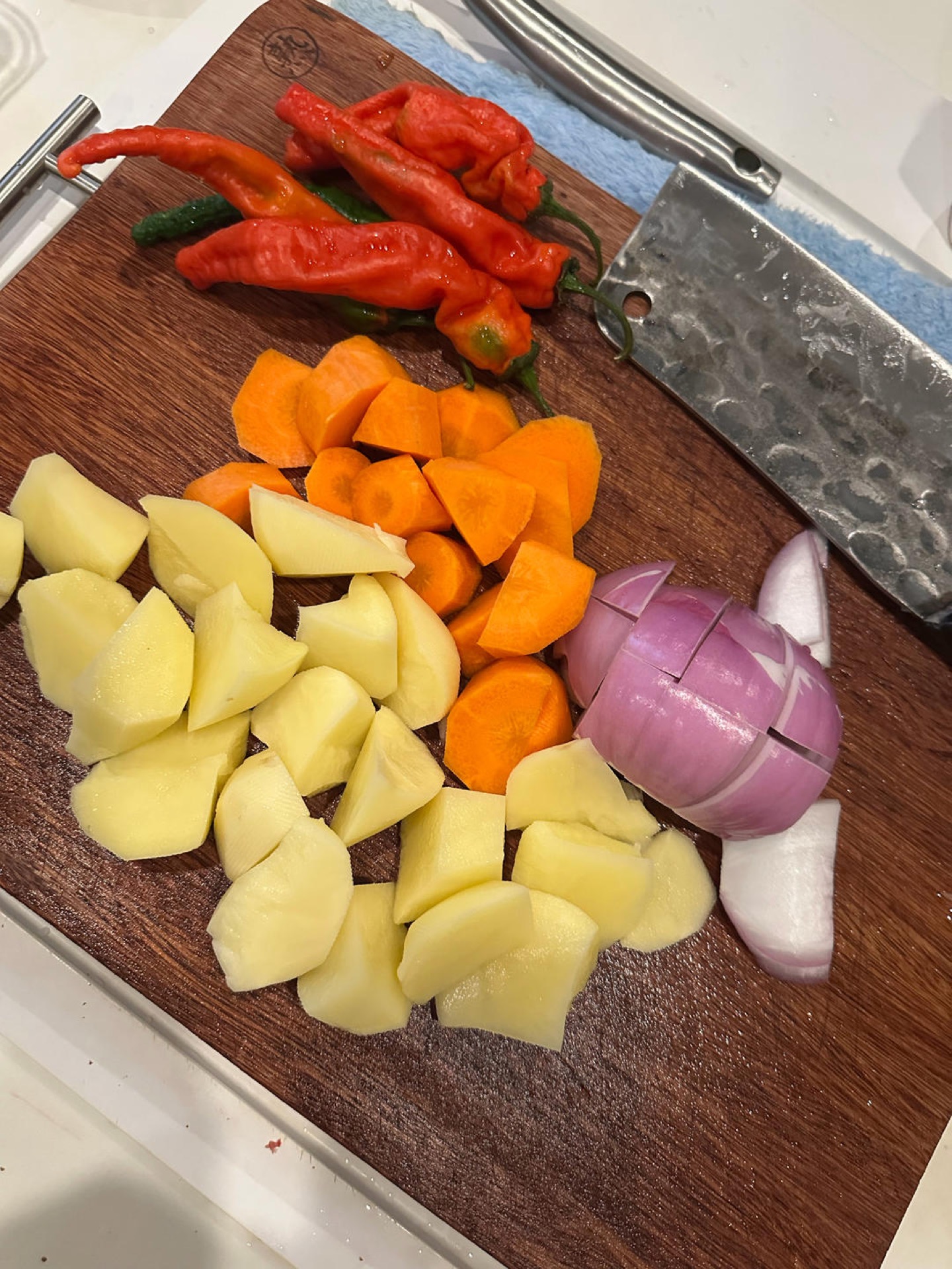 Cut the onion, potatoes, and carrot into rolling chunks, and the chili peppers into pieces. (King oyster mushrooms, shiitake mushrooms, lettuce stems, lotus root slices, and corn c