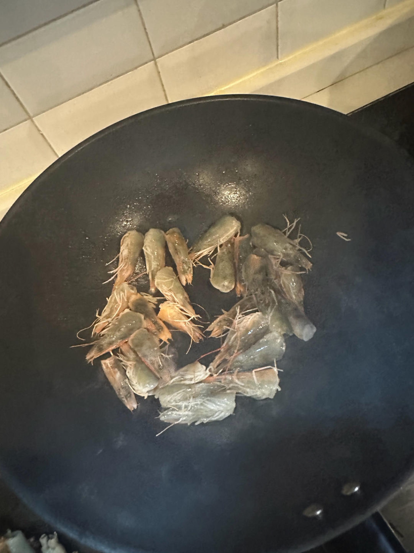 Heat a wok and add lard for a richer flavor — any oil works if you do not have lard. Fry the shrimp heads until fragrant and the oil turns orange-red.