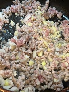 Once the pork changes color, add half of the scallion, ginger, and garlic.