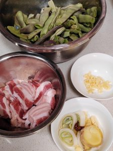 Slice the pork belly thinly, cut the scallions into segments, slice the ginger, smash the garlic and cut it into large chunks, then separately mince a little garlic and slice a lit