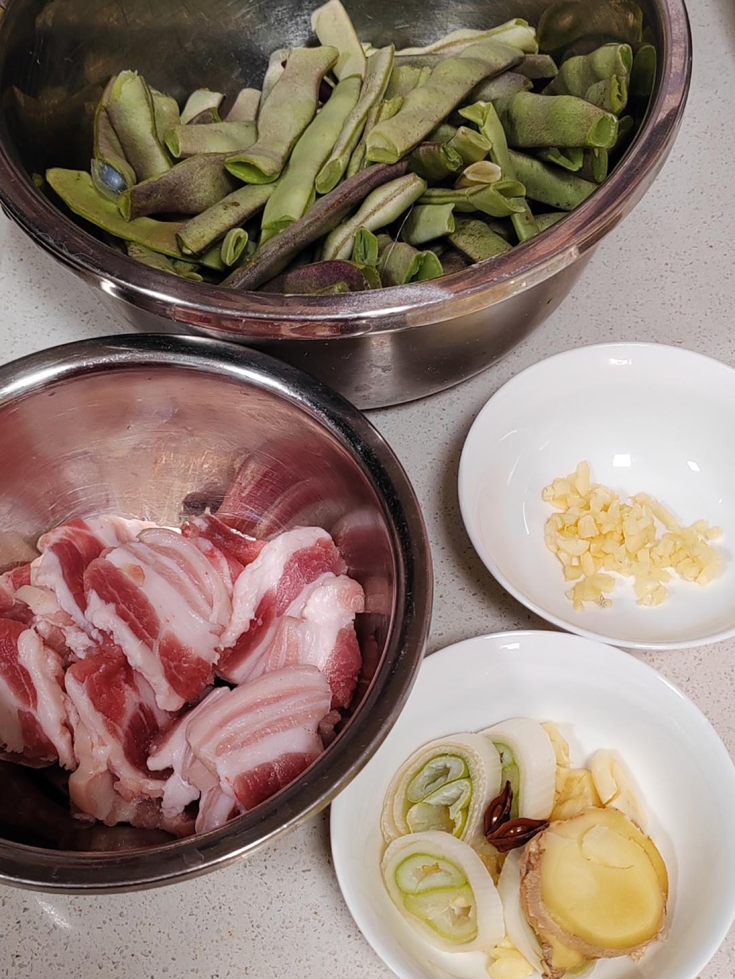 Slice the pork belly thinly, cut the scallions into segments, slice the ginger, smash the garlic and cut it into large chunks, then separately mince a little garlic and slice a lit