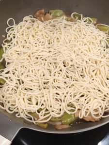 Remove the lid and spread the noodles loosely over the green beans, which should now be soft with the broth sitting beneath them, then cover and steam for about 5 more minutes.