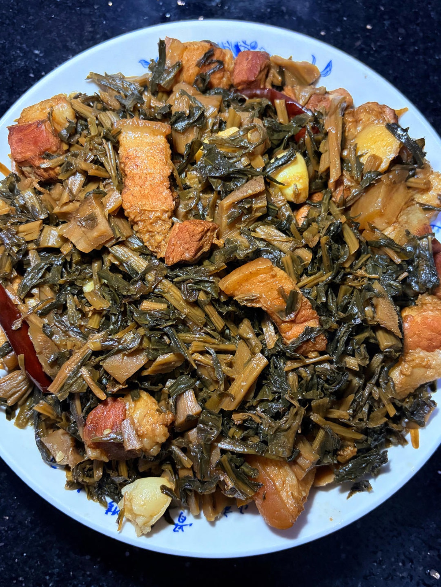 Braised pork belly with dried greens in a clay pot