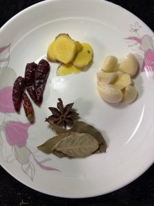 Ginger, garlic, dried chilies, star anise and bay leaves on a plate