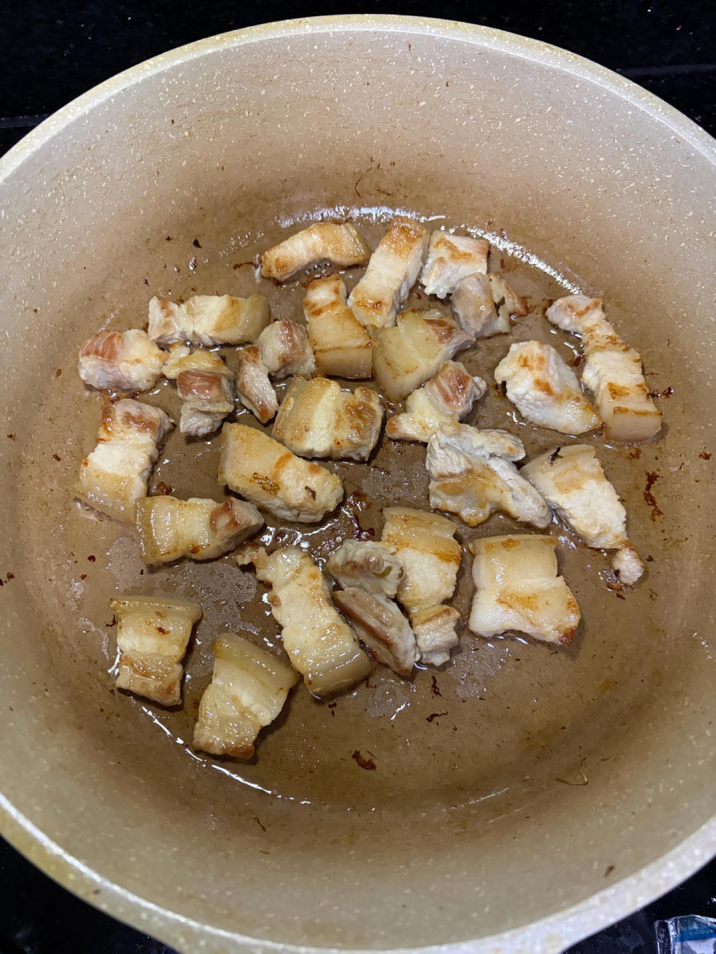 Pork belly rendering with aromatics in the wok