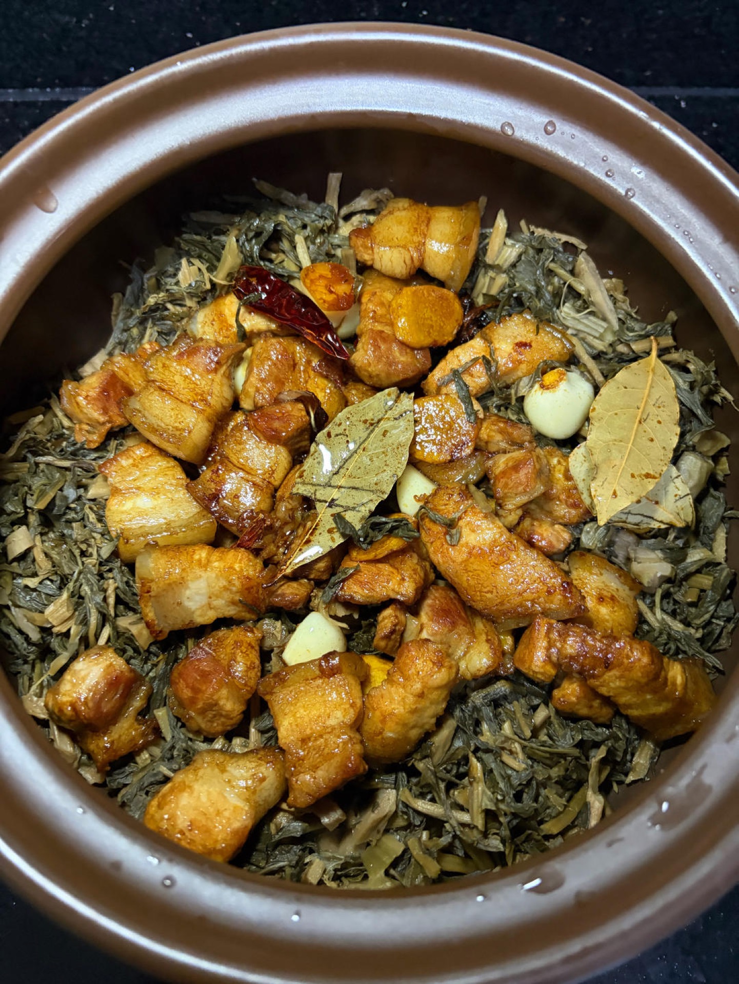 Pork belly poured over the greens in the clay pot