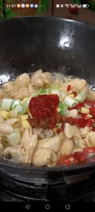 Add the scallions, sliced garlic, dried chili segments, star anise, and 1 tablespoon of doubanjiang, stirring until fragrant. A piece of hot pot base can be added too if you like.