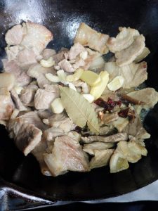 When the oil in the wok turns clear, pour the rice wine or cooking wine down the side of the wok, then add the ginger and the rest of the aromatics and stir-fry.