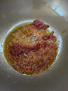 Pixian doubanjiang blooming in red oil in a wok