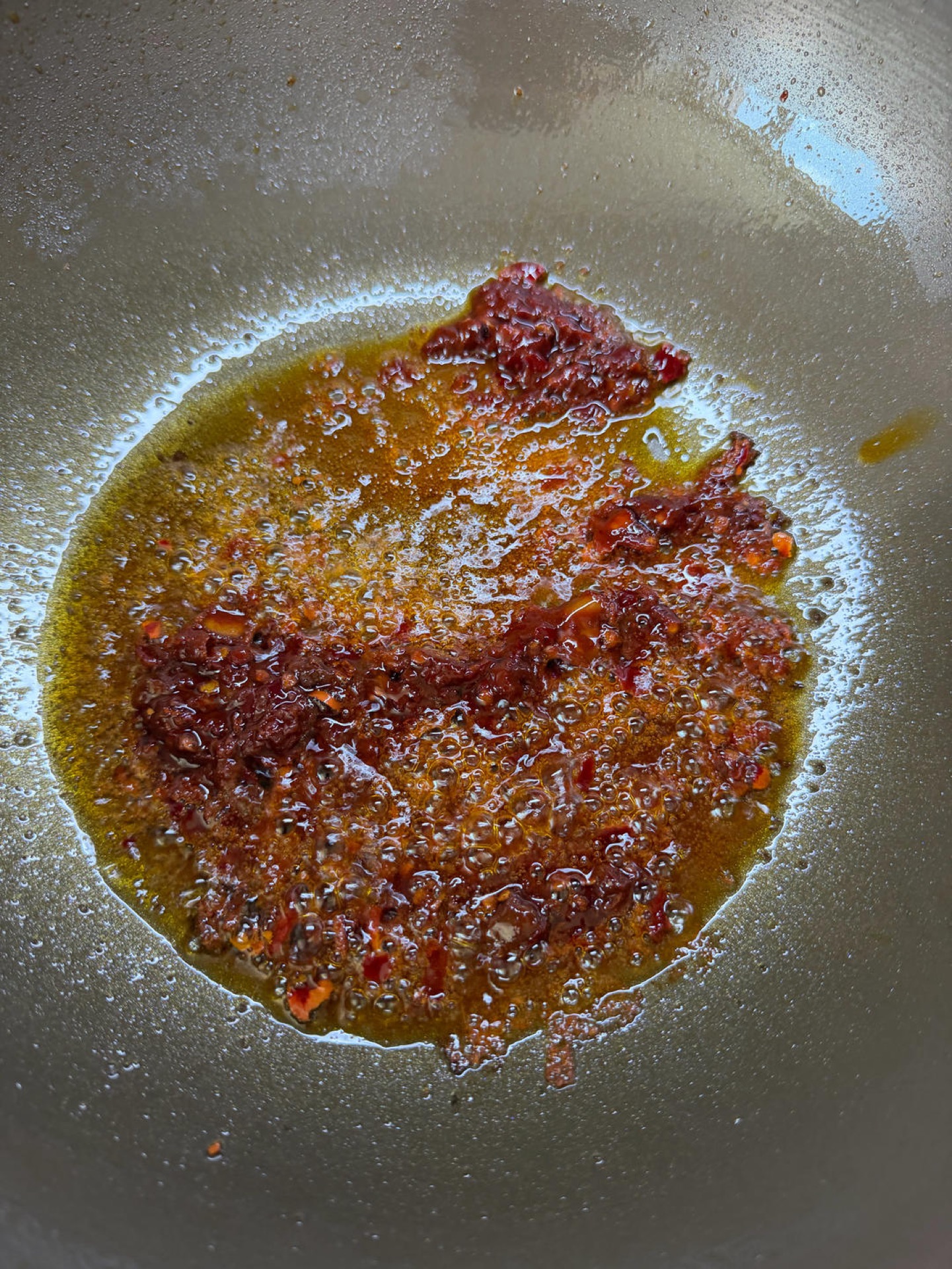 Pixian doubanjiang blooming in red oil in a wok