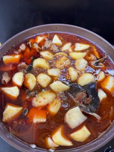 Finished braised river fish with potatoes in a dark pot
