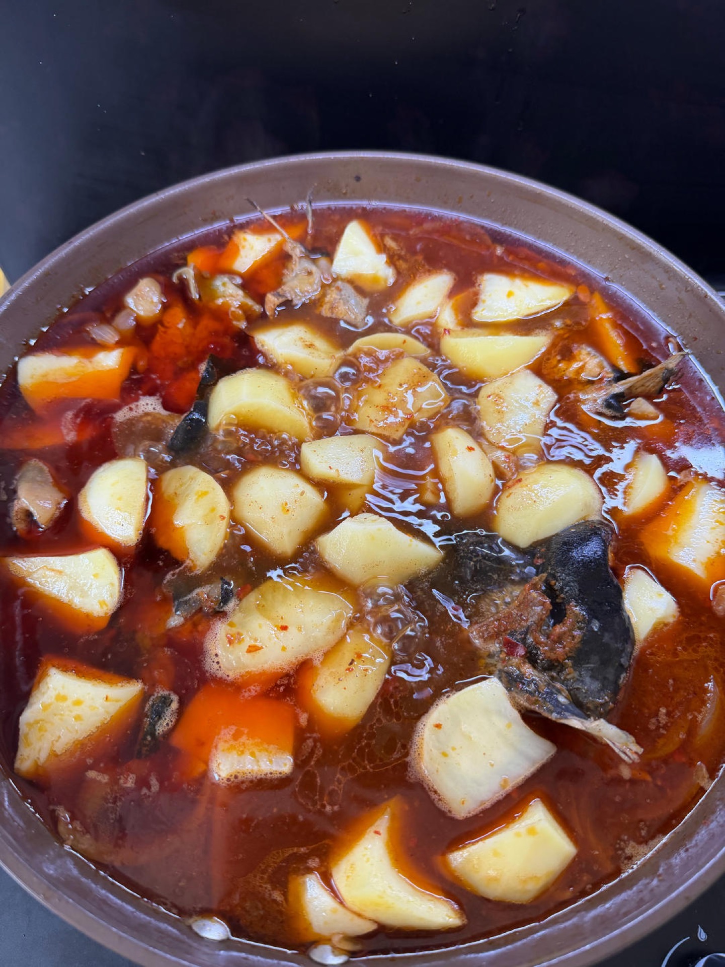 Finished braised river fish with potatoes in a dark pot