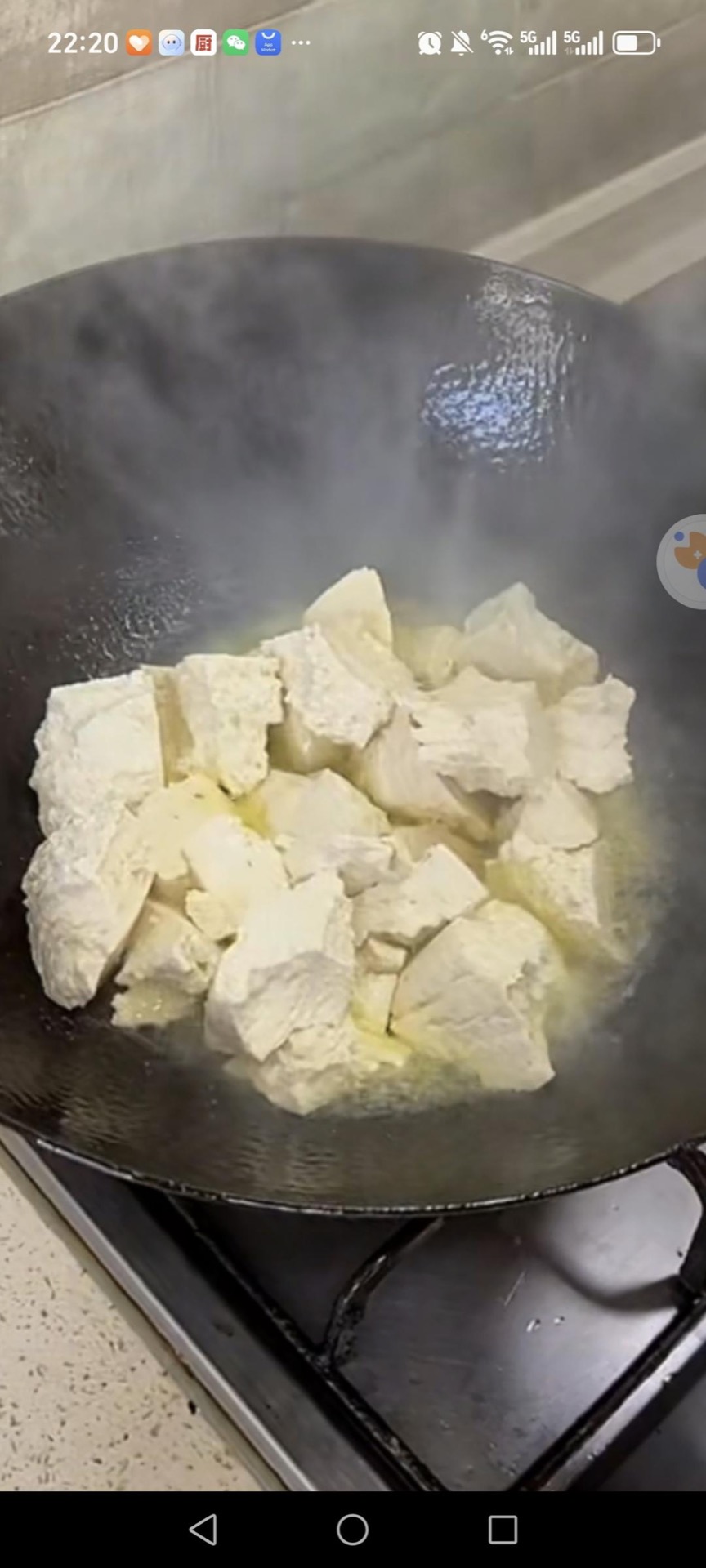 Heat a wok with oil, sprinkle in a pinch of salt, and slide the tofu cubes in to pan-fry.