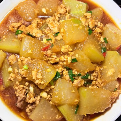 Braised winter melon with minced pork in a clay pot, glossy cubes of winter melon topped with scallion