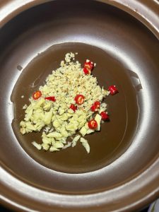 Preheat the clay pot, add the oil, tip in all the aromatics, and fry them over low heat until fragrant.