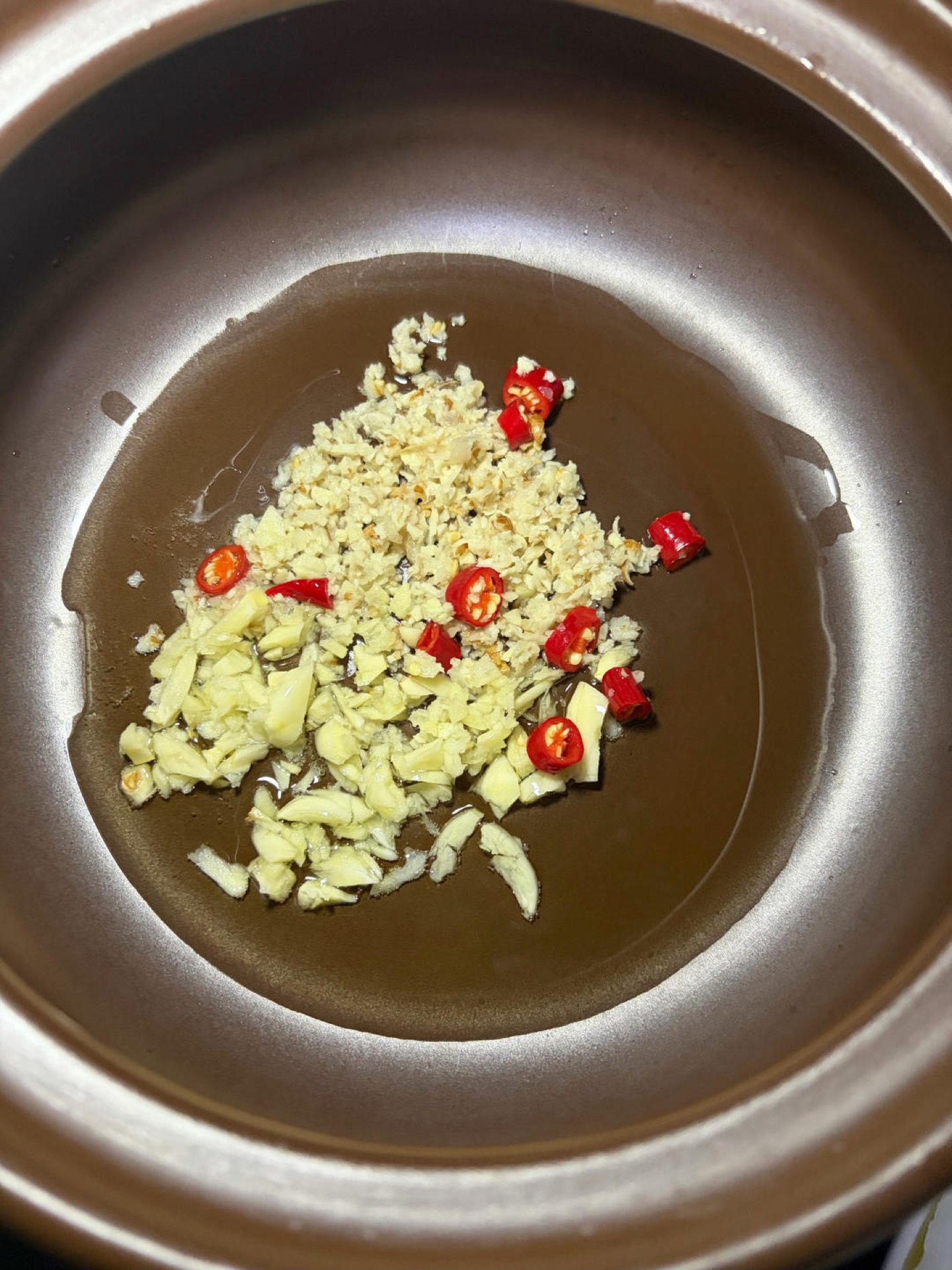Preheat the clay pot, add the oil, tip in all the aromatics, and fry them over low heat until fragrant.