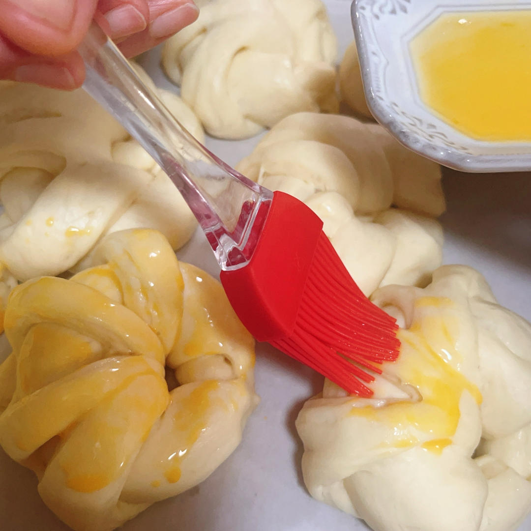 Brushing the proved buns with egg wash