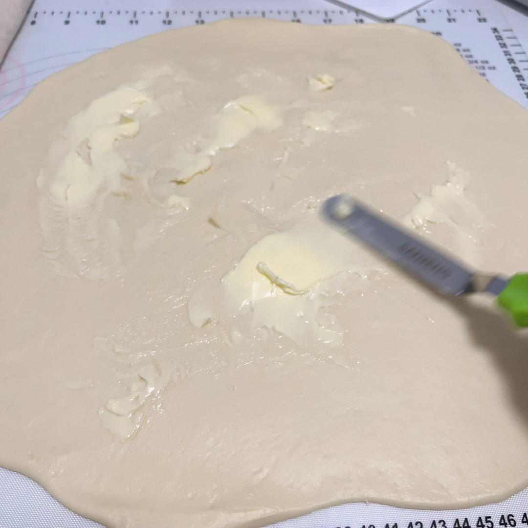 Rolling the dough into a round and spreading butter over it
