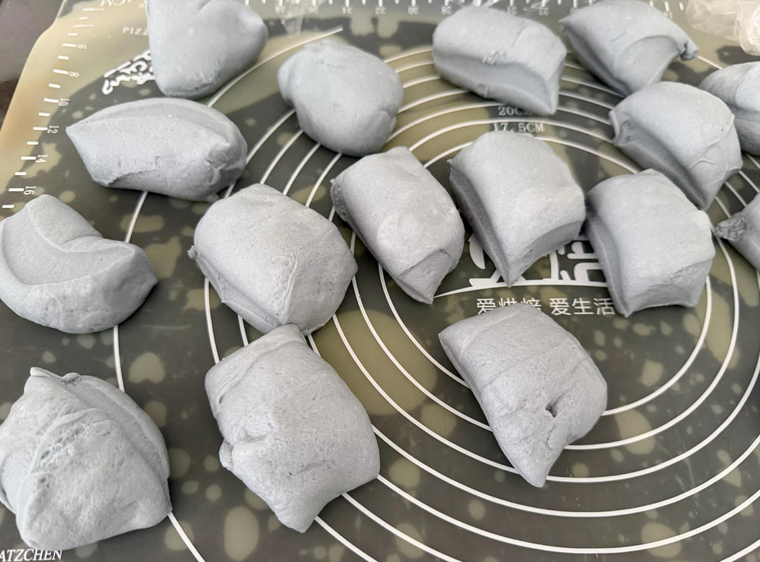 Blue buns filled with cheese being rounded and proofed