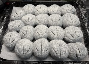 Proofed blue buns dusted with flour and slashed
