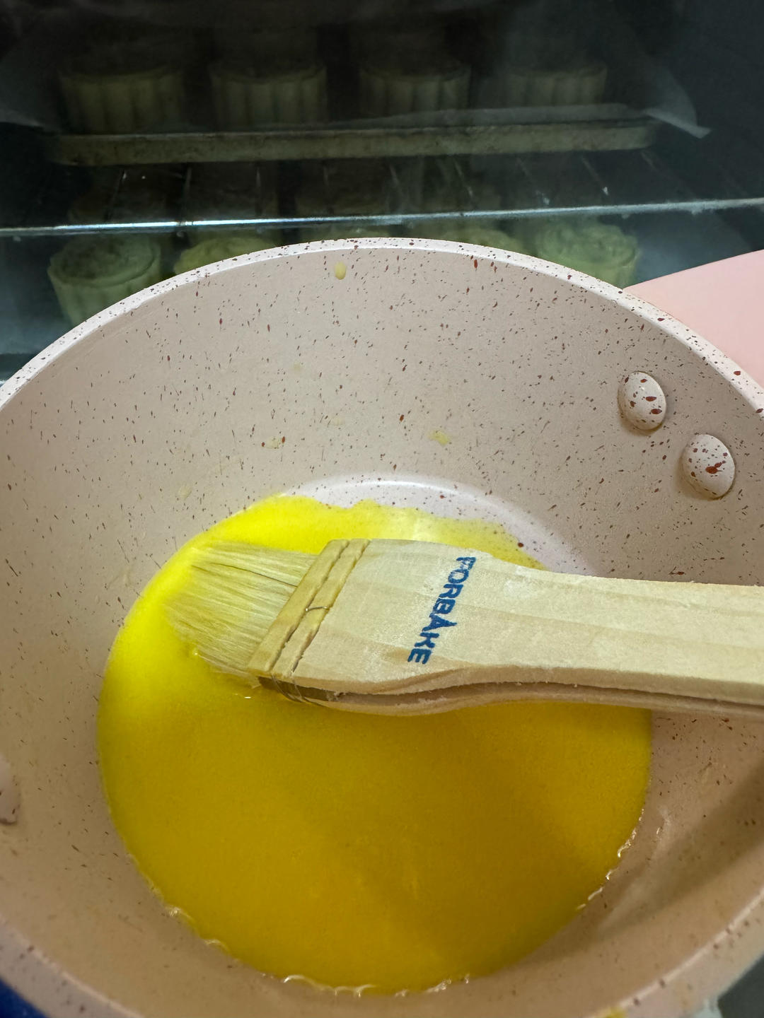 Egg wash being brushed onto the mooncakes