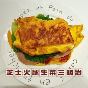 Cheese ham lettuce egg toast on a plate with a molten cheese pull and crisp lettuce
