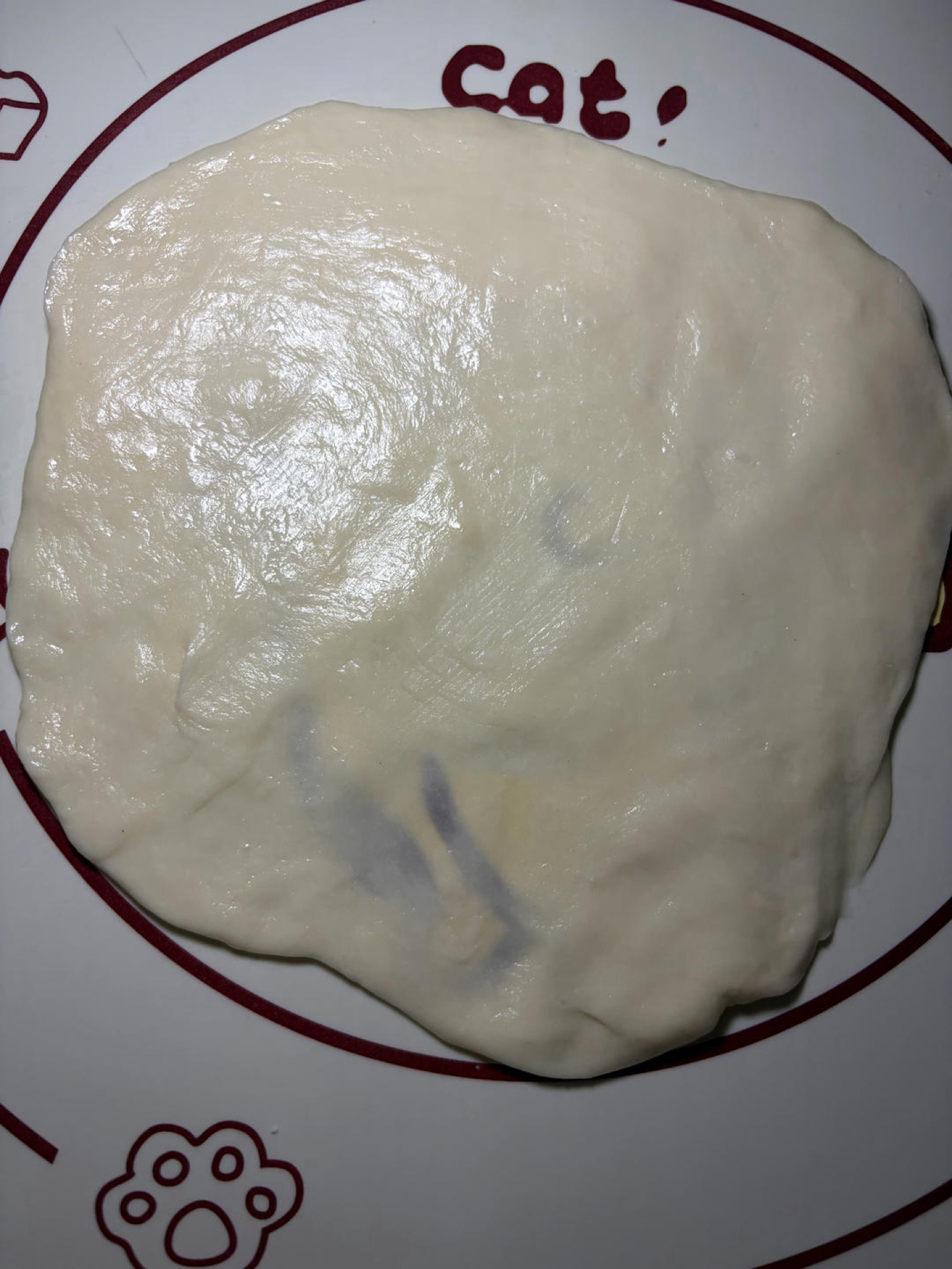 Take one piece of dough onto a mat, put on gloves, and press it flat with your palm, then stretch it into a very thin wrapper; you do not even need a rolling pin because the dough