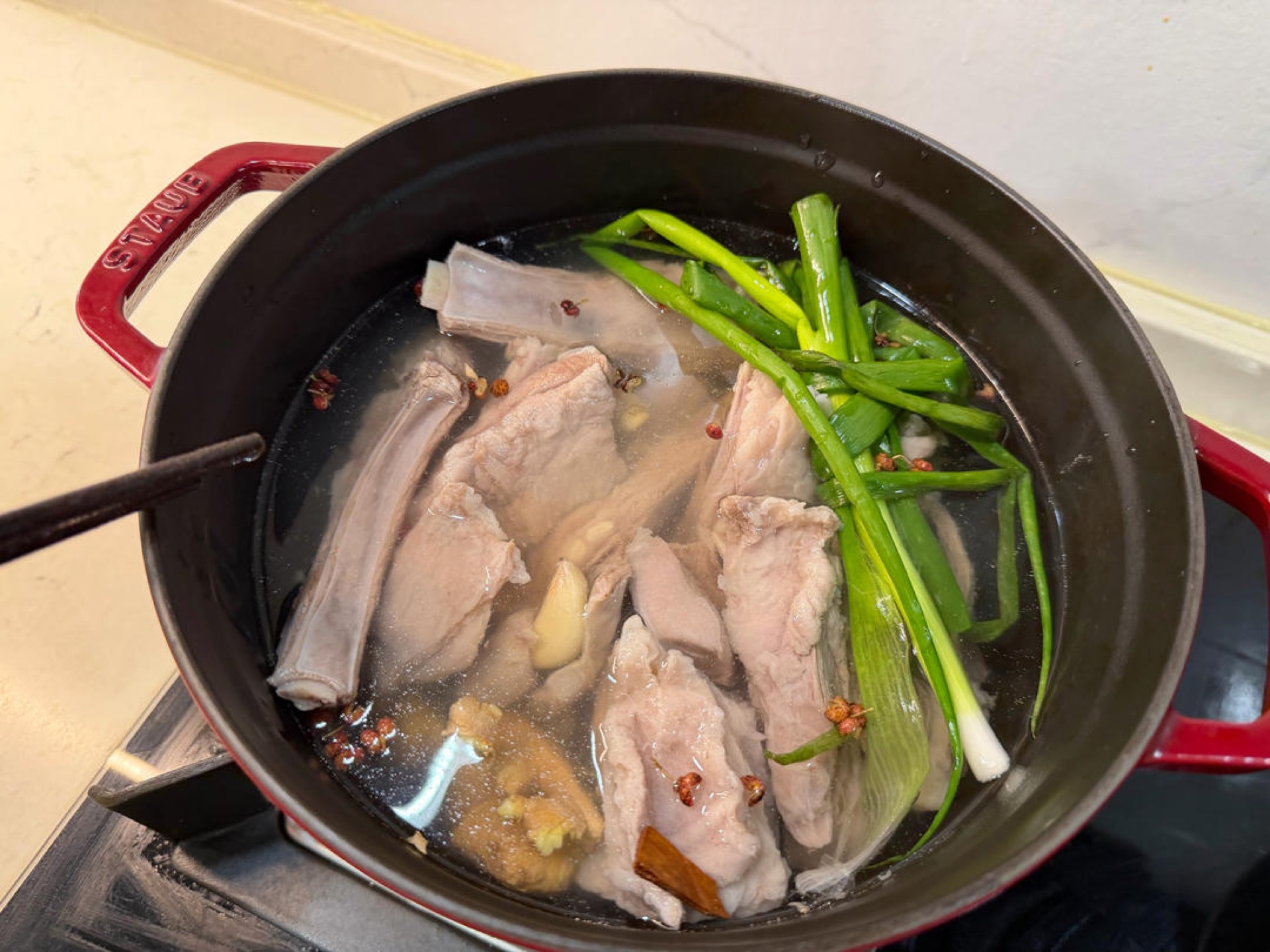 Add the washed lamb, the scallion, ginger and garlic to the pot, along with the Sichuan peppercorns and a small piece of cinnamon bark (which you can also leave out), pour in a lit