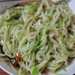 Cold tossed gourd salad in a white bowl, garnished with chili and sesame