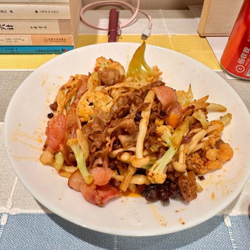 Dry pot bacon and mushroom stir-fry in a wok with cauliflower, seafood mushrooms, and bacon