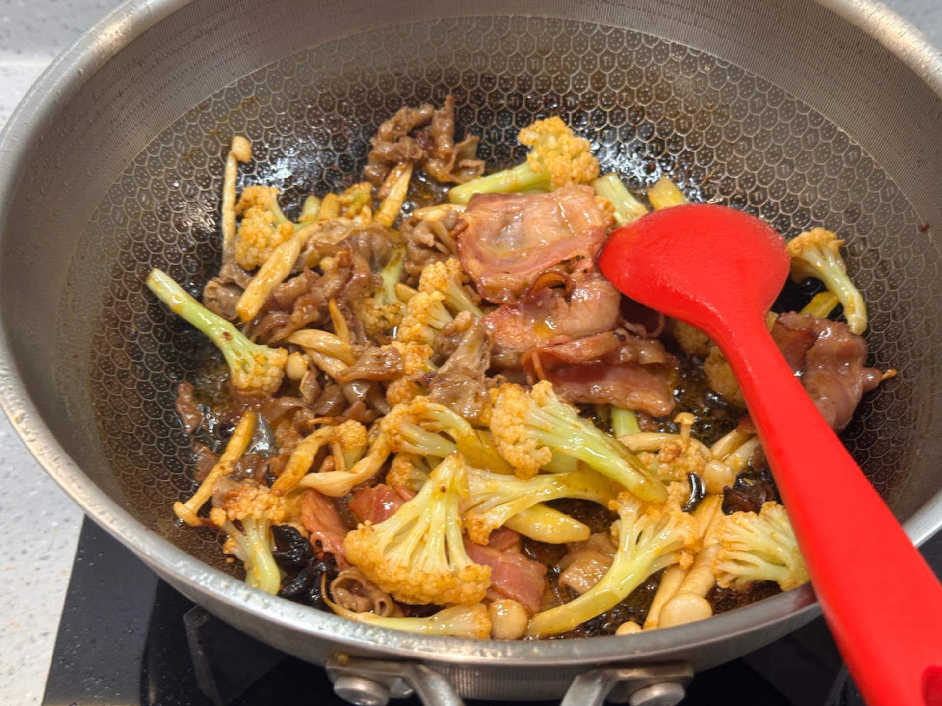 Add the bacon and meat rolls, stir-fry until they just begin to change color, then add an appropriate amount of dry pot sauce and stir-fry.