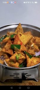Scatter the thinly sliced onion over the bottom of a dry pot or serving dish, spoon the tofu and pork over it, and serve immediately while the onions soften under the hot sauce.