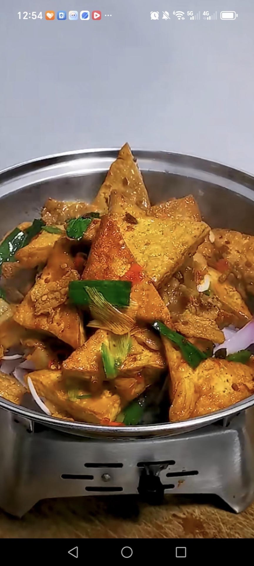 Scatter the thinly sliced onion over the bottom of a dry pot or serving dish, spoon the tofu and pork over it, and serve immediately while the onions soften under the hot sauce.